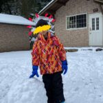 雪玉に手をかける子どもとバンガローの写真