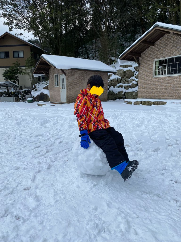 雪玉の上に座るこどもとバンガローの写真